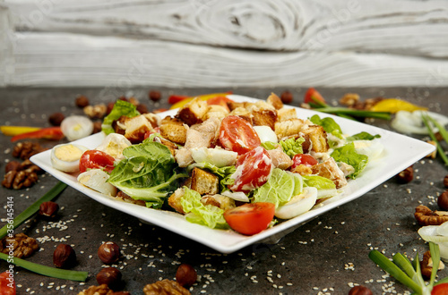 Greek salad on a white square plate. Dark textured background