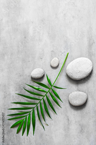 Flat lay composition with spa stones, palm leaves on grey background.