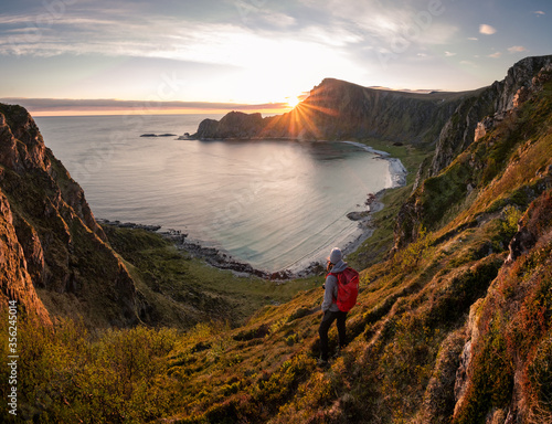 A woman hiking during midnight sun. Active vacation in Norway. Located on Andøya island in Vesterålen north of Norway. Sunset and backpack girl.