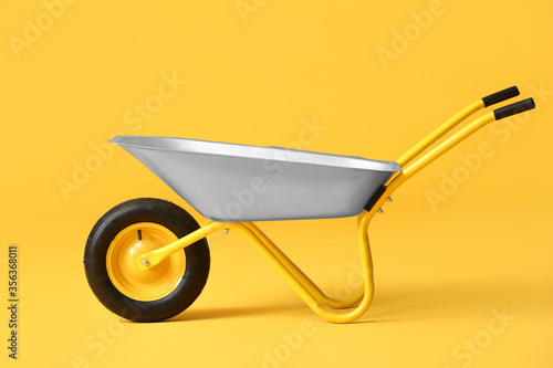 Empty wheelbarrow on color background
