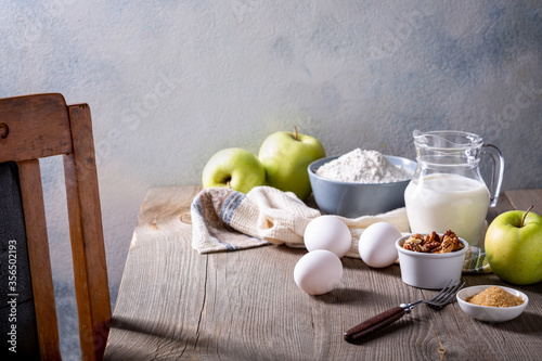 Milk, flour, eggs and green apples on a wooden table. Ingredients for apple charlotte