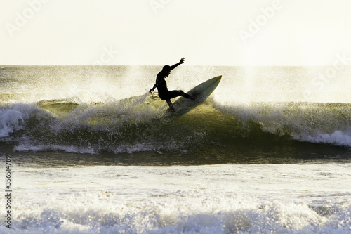 Silhouette man surfing waves at Arraial do Cabo, Rio de Janeiro. Surfer in action at stunning beach, Praia Grande, tropical lifestyle, during a scenic sunset, backlit, isolated. Outdoors radical sport