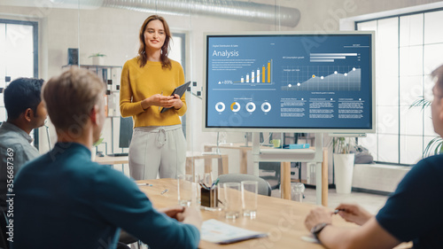 Female Chief Analyst Holds Meeting Presentation for a Team of Economists. She Shows Digital Interactive Whiteboard with Growth Analysis, Charts, Statistics and Data. People Work in Creative Office.