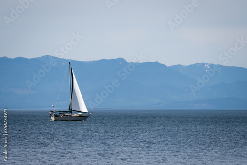 Sailing boat with mountains in backdrop, shot on Vancouver Island, British Columbia, Canada