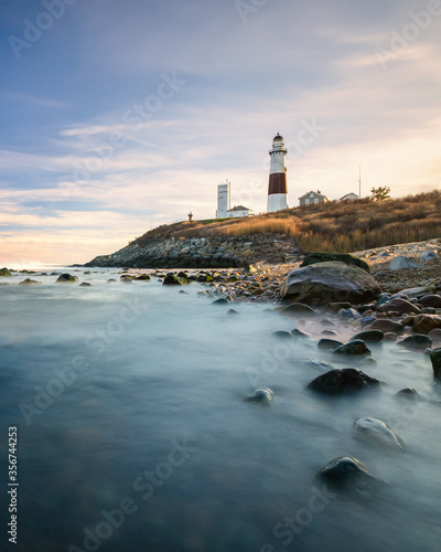 Lighthouse beacon sitting on a cliff overlooking the ocean during sunset. Montauk State Park, New York