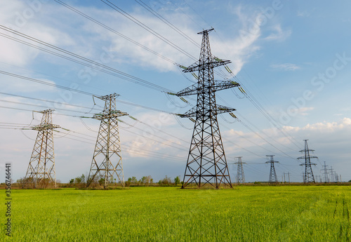 Electrical net of poles on a panorama of blue sky and green meadow