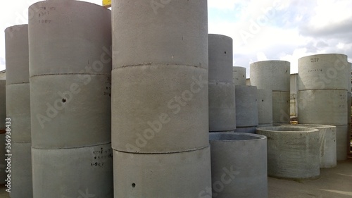Row of Reinforced concrete rings. Products for well. Water supply construction. Sewer Materials. Cylinder Pipe. Pipeline engineering. Industry manufacturing. Industrial background