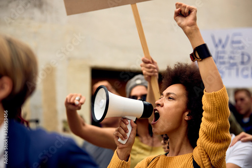 Yung black woman shouting through megaphone on anti-racism demonstrations.