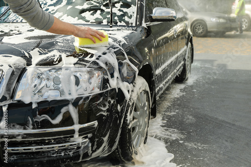 Man wipes the car with a sponge. Car wash. Clear car concept