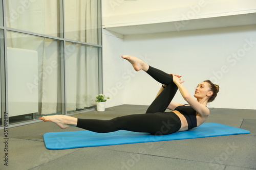 young woman doing pilates exercises in the gym