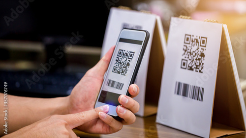 Closeup of a hand holding phone and scanning qr code. Man hand paying with qr code. Customer hand making payment through smart phone and scan code. Selective focus.