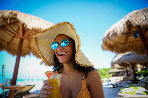 smiling woman on beach drinking a cocktail