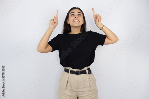 Young beautiful woman standing over white isolated background smiling and pointing up