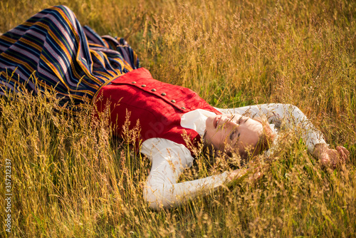 Latvian woman in traditional clothing in field.