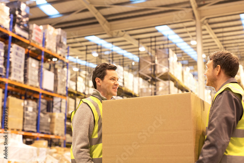 Workers carrying box in warehouse