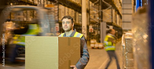 Worker carrying box in warehouse