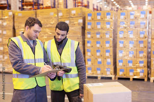 Workers writing on clipboard in warehouse