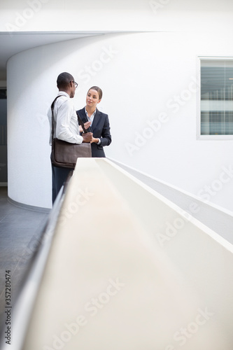 Businessman and businesswoman talking in office corridor