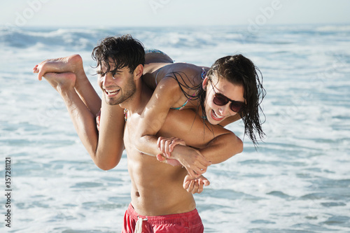 Happy man carrying woman on beach