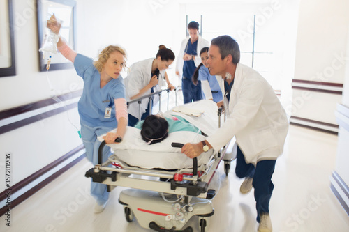 Doctors rushing patient on gurney in hospital corridor