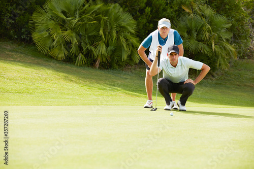 Caddy and golfer preparing to putt