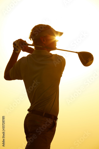 Silhouette of man swinging golf club