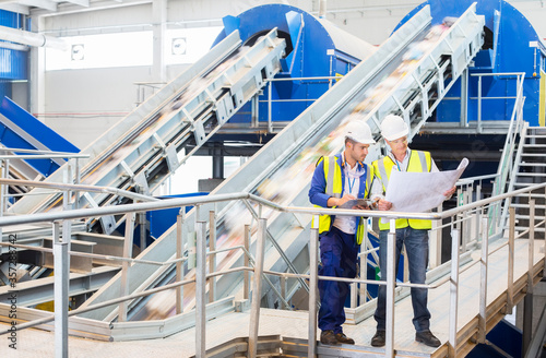 Workers reading blueprints in recycling center