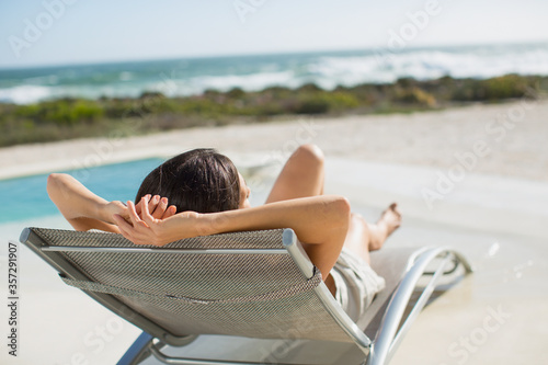 Woman sunbathing on lounge chair at poolside