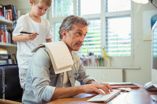 Son distracting father at work in home office