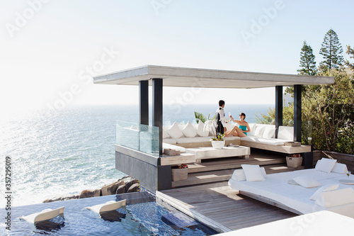 Waiter serving woman drinks at cabana overlooking ocean