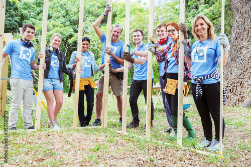 Portrait smiling volunteers holding construction frame at construction site