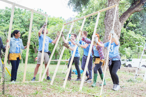 Volunteers lifting construction frame at construction site