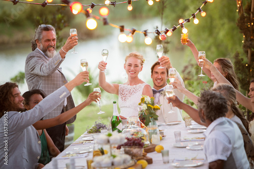 Young couple their guests toasting champagne during wedding reception in garden
