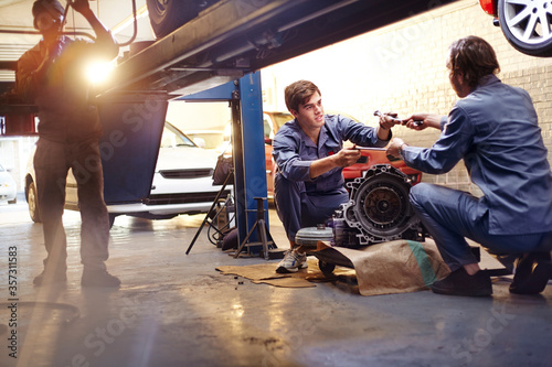 Mechanics discussing part in auto repair shop