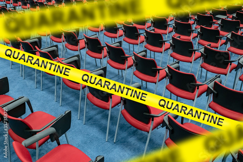 An empty room with rows of chairs behind a yellow tape marked Quarantine. Ban on visiting public places. Self-isolation mode due to coronavirus. Restrictions to prevent the spread of the disease.