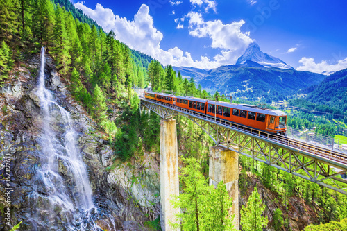 Zermatt, Switzerland. Gornergrat tourist train with waterfall, bridge and Matterhorn. Valais region.