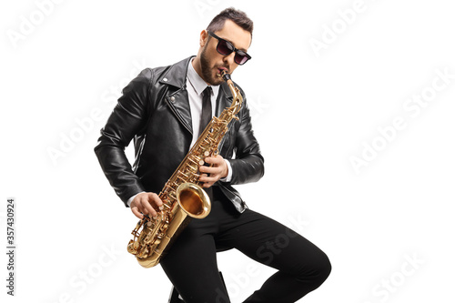 Male musician in a leather jacket sitting and playing a saxophone
