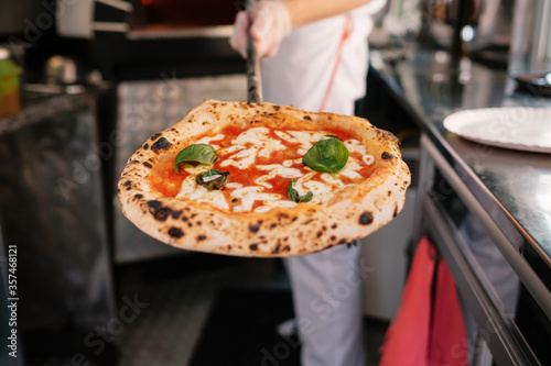 The process of making pizza. The cook shows the pizza that he got out of a wood-fired oven.