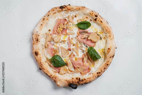 Italian pizza with mushrooms, basil and ham on a white background.