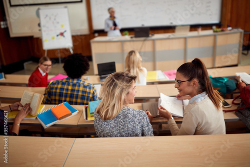Female students discussing while having lecture
