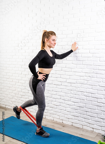 woman exercising legs at home using rubber resistance band
