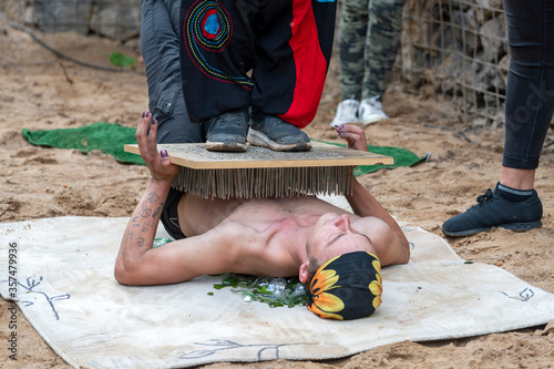 Fakir auf Glasscherben liegend mit Nagelbrett