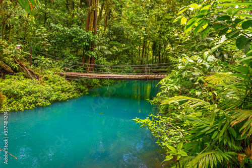 Rio Celeste with turquoise, blue water and small wooden bridge across the river Tenorio national park Costa Rica. Central America.