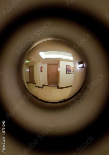 A corridor, lamps, a floor and two neighboring doors are visible in the door peephole