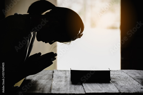 silhouette of teenage girl hand with bible praying in the morning.