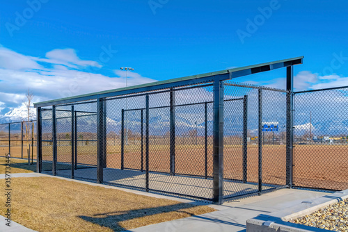Baseball field dugout with slanted roof and chain link fence on a sunny day