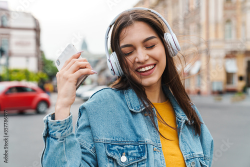 Image of woman listening music with smartphone and wireless headphones