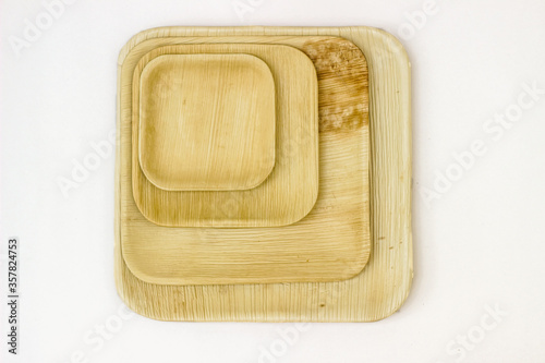 Four Square Areca leaf plates. Top view on a white background.