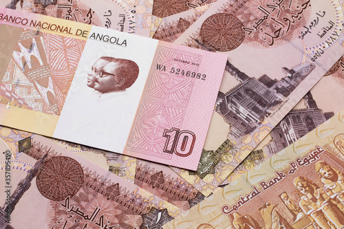 An red and white ten Angolan kwanza bank note on a background of Egyptian one pound bank notes