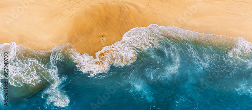 Aerial view of blue ocean waves in Kelingking beach, Nusa Penida island in Indonesia. Beautiful sandy beach with blue sea. Lonely sandy beach with beautiful waves. Beaches of Indonesia. Copy space